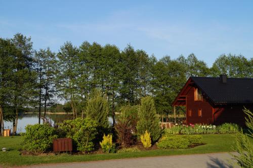 a red barn in a garden with a lake at Vila Viesai in Trakai