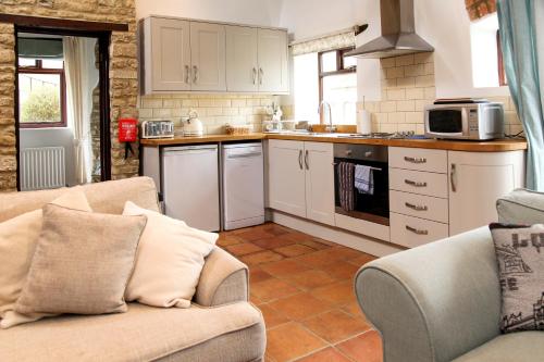 a living room with a couch and a kitchen at Stable Cottage, Oxfordshire in Oxford