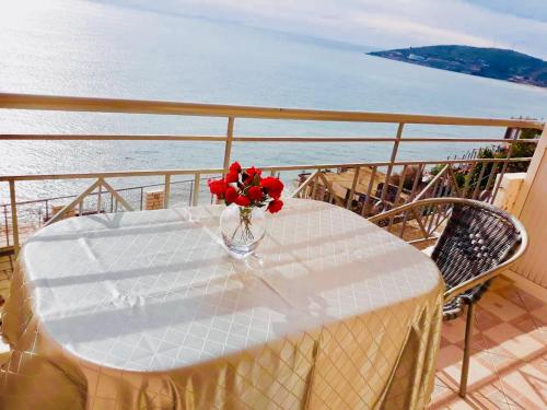 a table with a vase of red flowers on a balcony at Ionian Bay Rooms in Qeparo