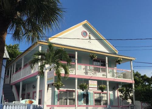 uma casa branca e rosa com uma palmeira em Caribbean House em Key West