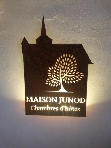 a sign on the wall of a building with a tree at Maison Junod in Romainmôtier