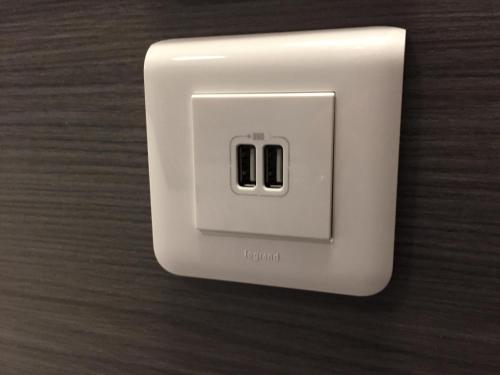 a white light switch on a wooden wall at Hôtel de L'Avenue in Tarbes