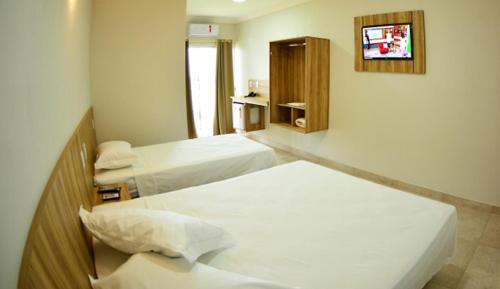 a hotel room with two beds and a tv at Dallas Palace Hotel in Rio Paranaíba