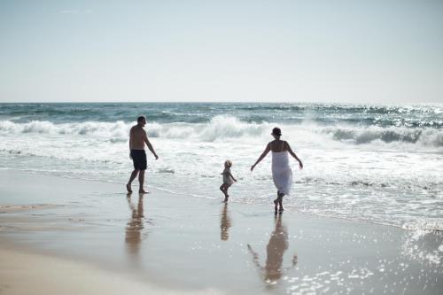 a man and a woman and a child walking on the beach at Bangalay Luxury Villas in Shoalhaven Heads