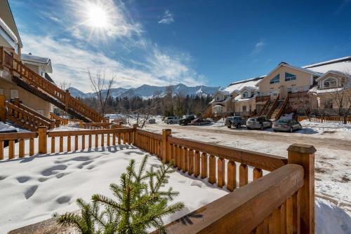 a house with a wooden fence in the snow at Riverside by FantasticStay in Fernie