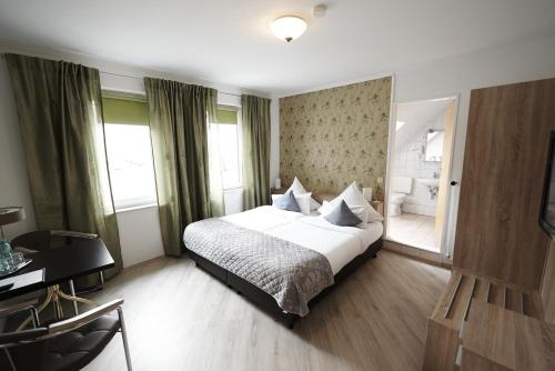 a bedroom with a bed and a desk and window at Hotel Wurster Kroog in Bremerhaven