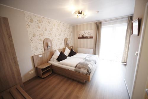 a bedroom with a bed with white sheets and a window at Hotel Wurster Kroog in Bremerhaven