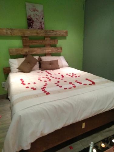a large bed with red rose petals on it at Lapa la Bakgatlha in Soweto