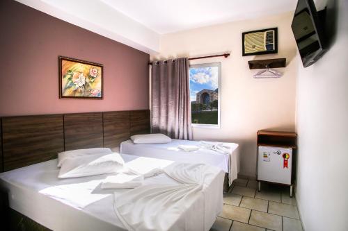 a room with two beds and a tv at Hotel Faenician in Aparecida