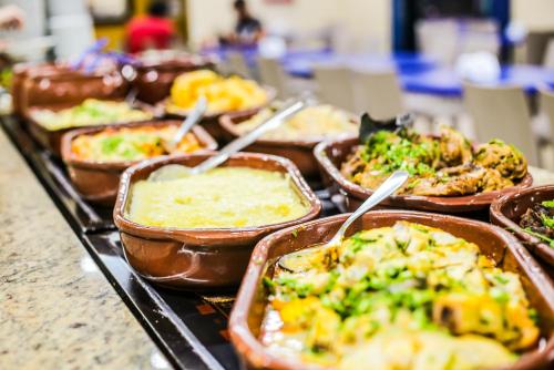 a buffet with many different types of food in trays at Hotel Faenician in Aparecida