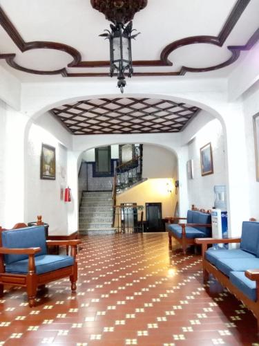 a lobby with blue chairs and stairs in a building at Hotel Virreynal in Córdoba