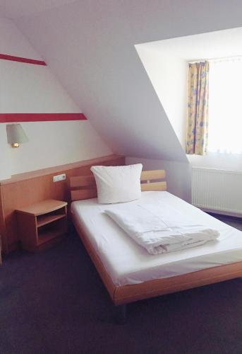 a bedroom with a white bed with a window at Gasthof Lindenwirt in Denkendorf