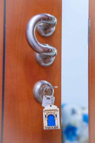 a metal door latch with a key and a house at Résidence chaounia d'hote in Chefchaouene