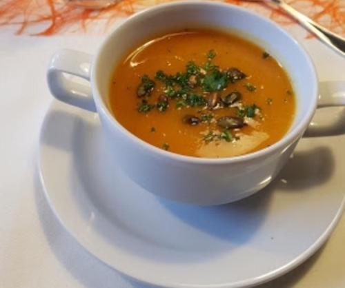 a bowl of soup on a plate on a table at Gasthof Lindenwirt in Denkendorf