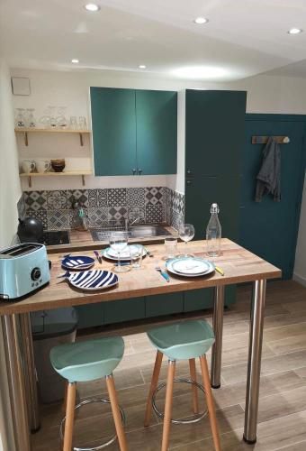 une cuisine avec des placards verts et une table en bois avec des chaises dans l'établissement Grand studio 35m2 centre ville, à LʼÎle-Rousse