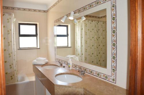 a bathroom with a sink and a mirror and a tub at Casa Maricel in Praia do Carvoeiro