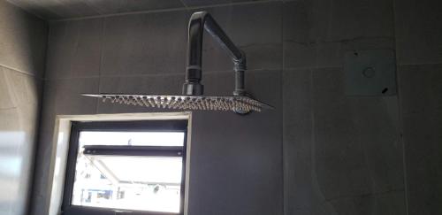 a shower head in a bathroom next to a mirror at El Suburbio - Morelos Sur in Morelia