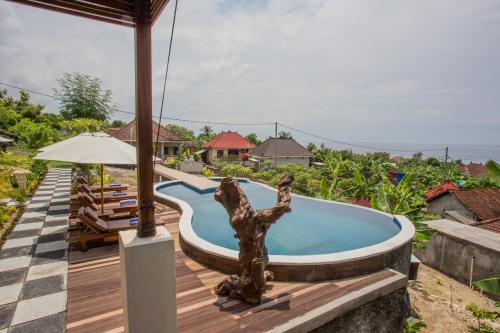 a pool at a resort with a statue next to a deck at Kabeh Jati Garden Villa & Restaurant in Nusa Penida