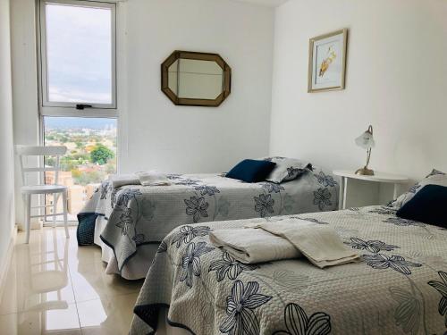 2 camas en una habitación blanca con ventana en ALOHA Güemes Premium, 2 dorm con Vista a las Sierras en Córdoba