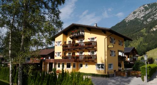 a large yellow building with balconies and a mountain at Appartements Waldruh in Achenkirch