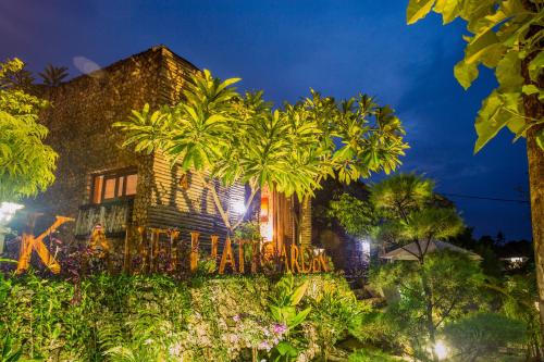 a house with palm trees in front of it at Kabeh Jati Garden Villa & Restaurant in Nusa Penida