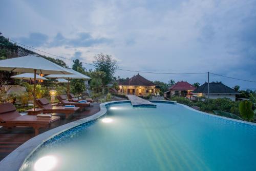a pool at a resort with chairs and umbrellas at Kabeh Jati Garden Villa & Restaurant in Nusa Penida