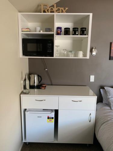 a small kitchen with a microwave and a bed at Blair Athol Accommodation in Balclutha