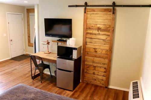 a room with a desk with a television and a wooden wall at Evergreen Motel in Libby