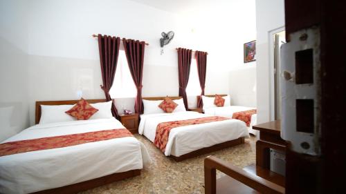 a bedroom with three beds with red and white sheets at KHÁCH SẠN MỸ NGỌC in Buon Ma Thuot