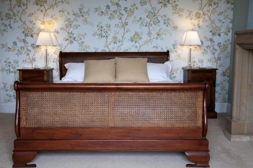a wooden bed in a room with two lamps at Amberley Inn in Stroud