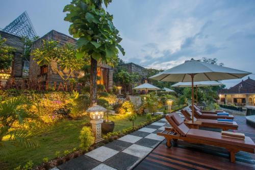 a patio with lounge chairs and an umbrella at Kabeh Jati Garden Villa & Restaurant in Nusa Penida