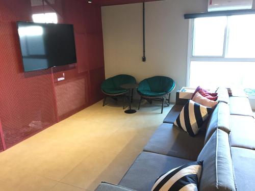 uma sala de estar com um sofá e uma televisão de ecrã plano em Artsy Vitoria Hostel em Vitória