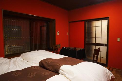 金沢市にあるレストラン＆イン 睦 金沢の赤い壁のベッドルーム1室(ベッド2台、窓付)