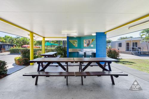 a group of picnic tables under a pavilion at Coral Coast Tourist Park in Townsville