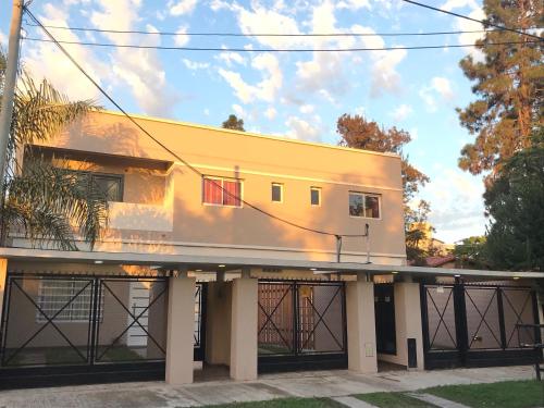 a large white house with a fence in front of it at Mendoza Apartments Ezeiza Airport in Luis Guillón