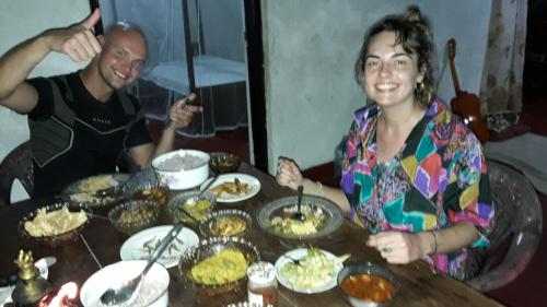 a man and a woman sitting at a table with food at Colonial Surfing Villa Hostel & Home Stay in Midigama