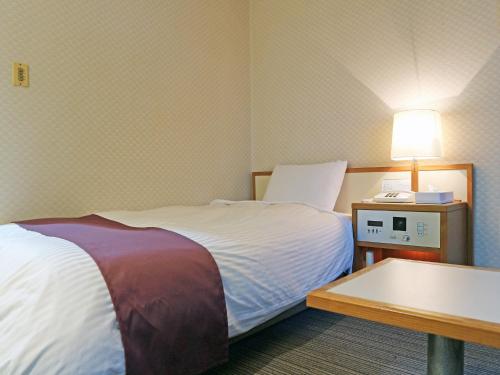 出雲市にあるホテル武志山荘のベッド1台、テーブル(ランプ付)