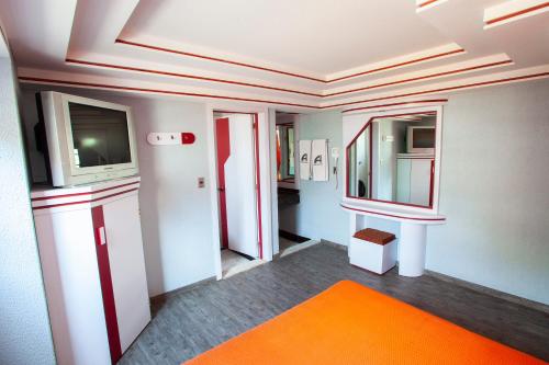 a bathroom with an orange rug and a tv at Hotel Ancona - S&oacute;lo Adultos in Mexico City