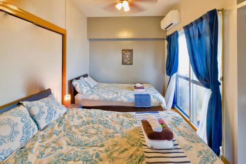 um pequeno quarto com 2 camas e uma janela em Holiday Homes TSUBOYA 505 em Naha