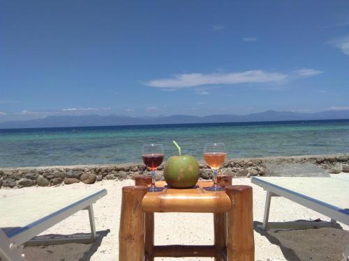 a table with two glasses of wine and an apple on the beach at Ancelle Cristo Re in Moalboal