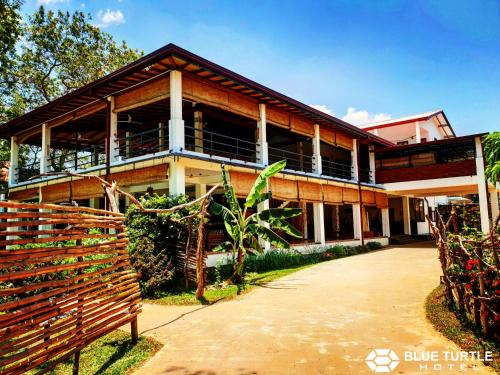 a house with a fence in front of it at Blue Turtle Hotel in Tissamaharama