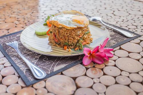 a plate with a sandwich and a flower on a table at Kabeh Jati Garden Villa & Restaurant in Nusa Penida