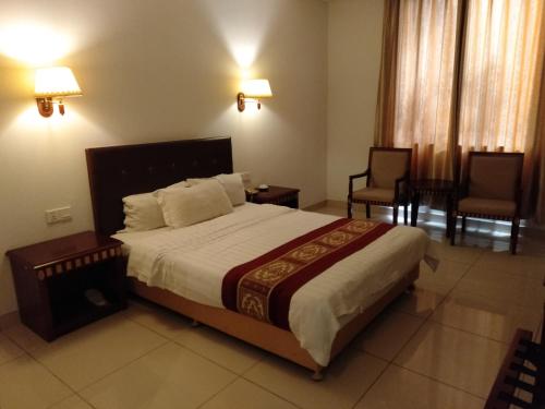 a bedroom with a large bed and two chairs at Beach Garden Hotel in Dili