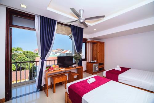 a bedroom with two beds and a desk with a television at Riverside Plum Garden Villa in Hoi An