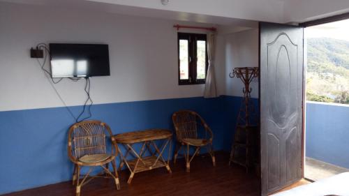 a room with three chairs and a table and a tv at Good Hotel in Bandipur
