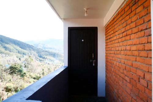 a room with a brick wall and a black door at Good Hotel in Bandīpur