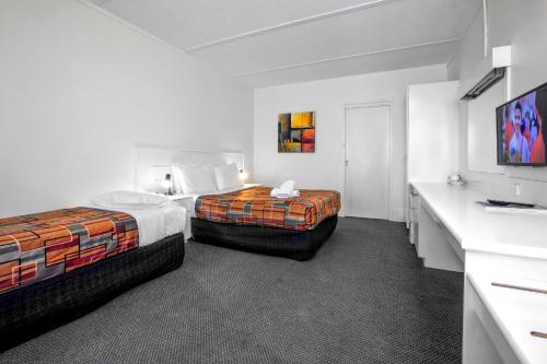 a hotel room with two beds and a flat screen tv at Parkside Inn Motel in Melbourne