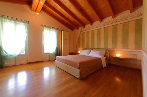 1 dormitorio con 1 cama, 2 ventanas y suelo de madera en Villa Zarina - ZAvillas - up to 12 people, en Peschiera del Garda
