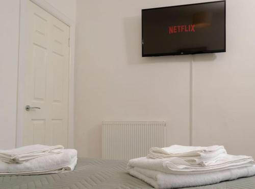 two towels sitting on a bed with a tv on a wall at Tranquil Place in Dundee near Docks in Dundee
