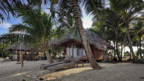 una pequeña cabaña con palmeras delante en Kimo Resort Pulau Banyak Aceh Singkil, en Alaban